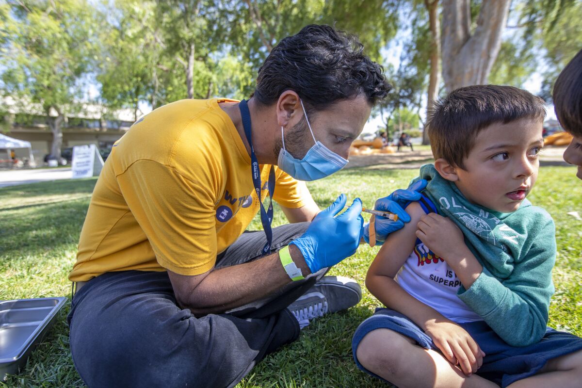 A health worker vaccinates a child in a park.