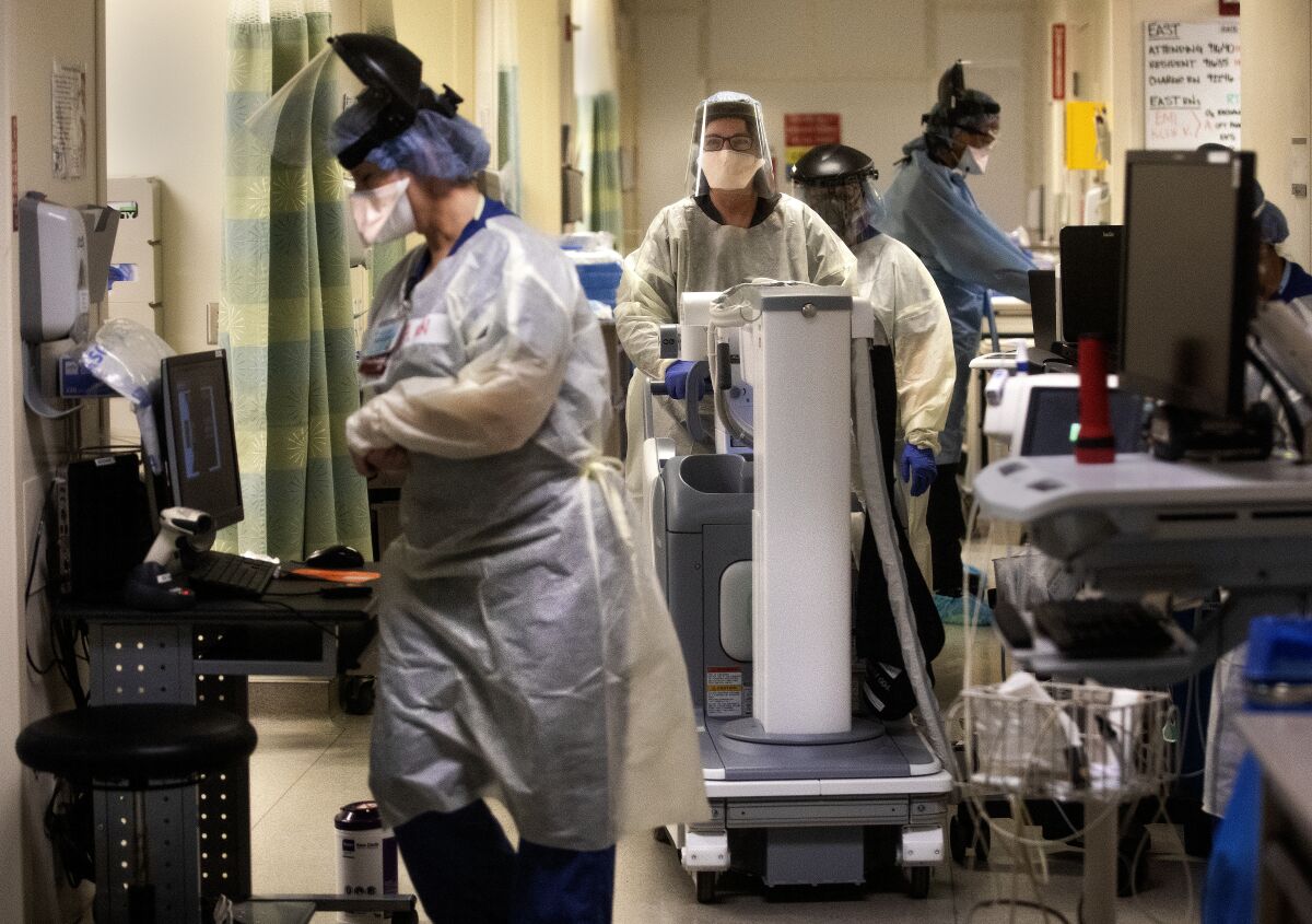 Medical staff, wearing protective gear, work inside a COVID-19 isolation area.