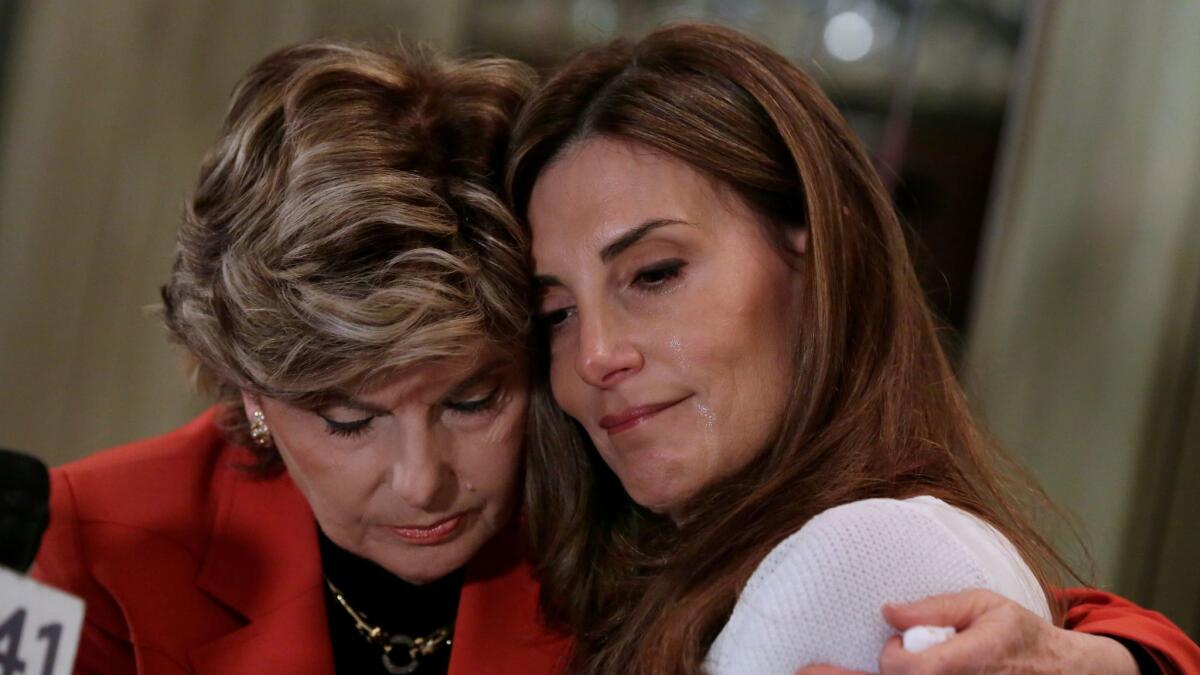 Karena Virginia, right, is hugged by lawyer Gloria Allred, during a news conference in New York on Oct. 20.