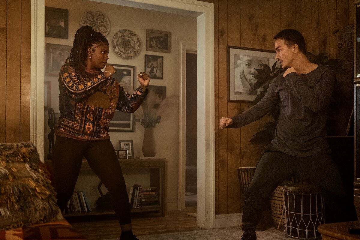A woman and man face each other in a living room, about to fight.