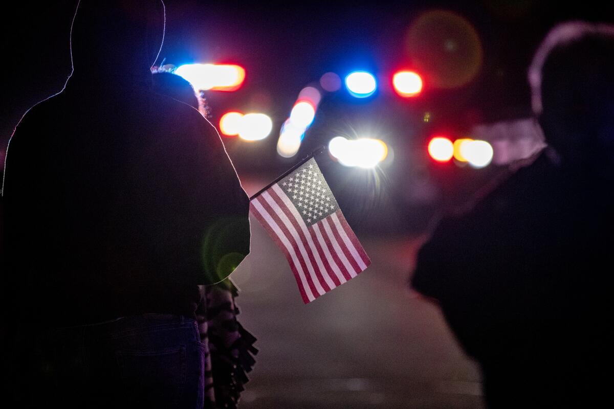 A person, in silhouette, holds an American flag.