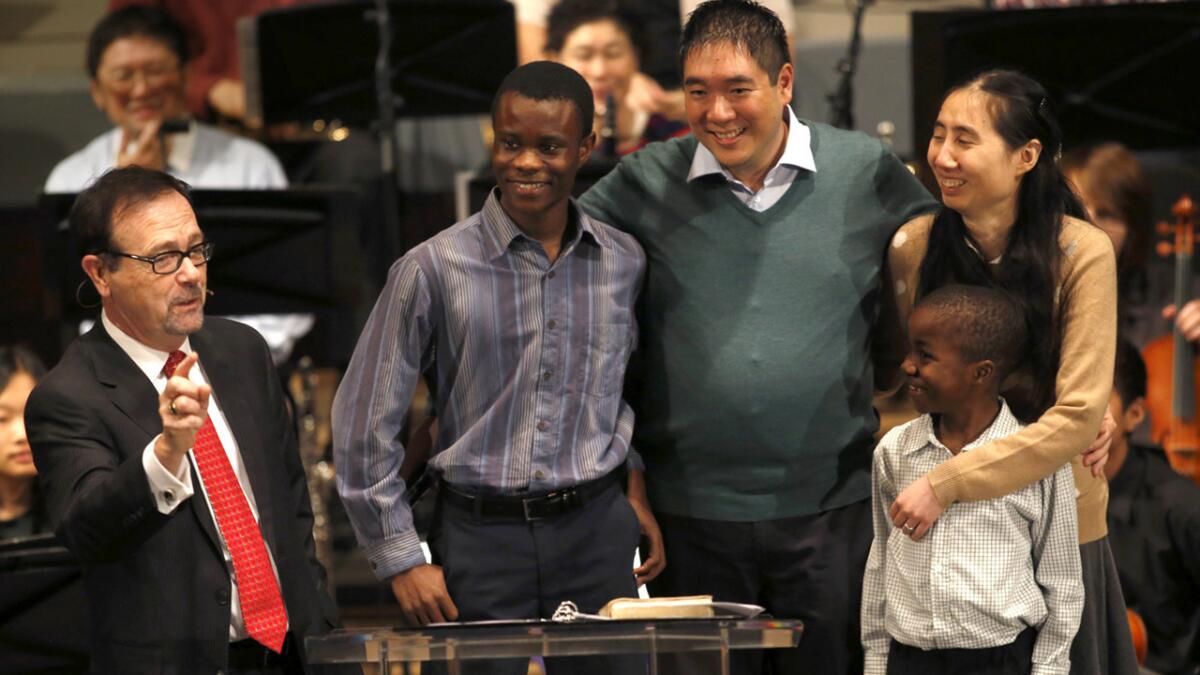 Pastor Greg Waybright, left, welcomes Matt and Grace Huang and their sons Immanuel, left, and Josiah on their return to the Lake Avenue Church in Pasadena on Sunday.