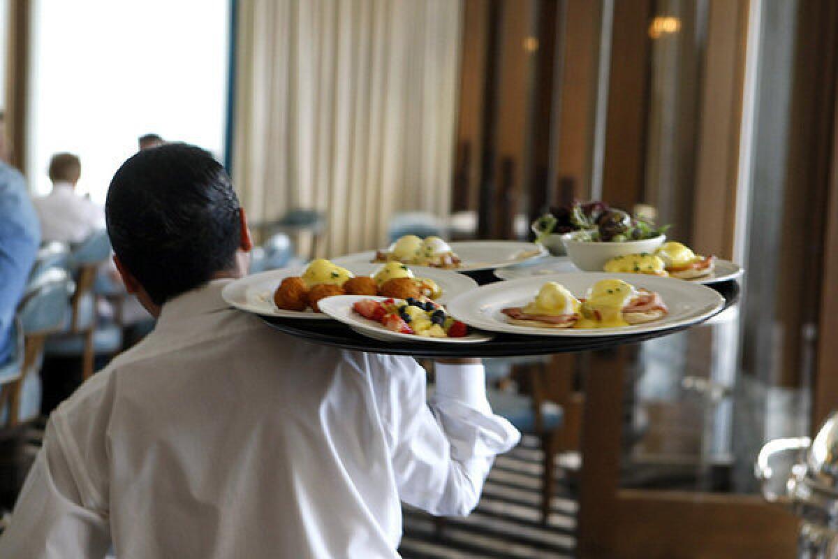 A waiter carries plated food to diners at Perle restaurant in Pasadena. 