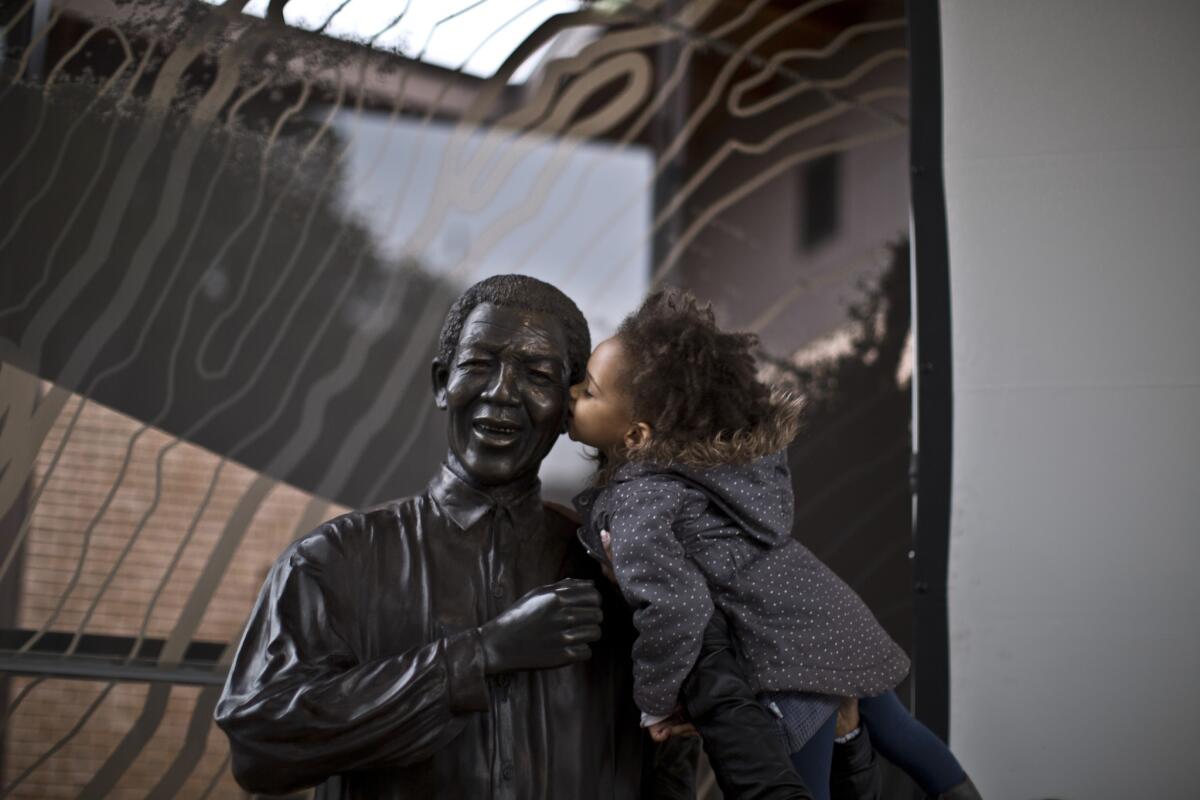 A girl held up by her mother kisses a statue of the late Nelson Mandela in Johannesburg, South Africa.
