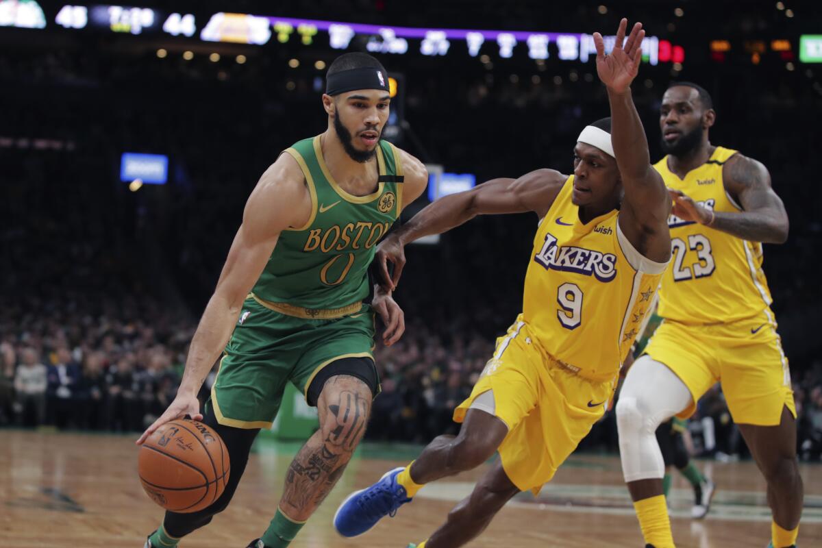 Boston Celtics forward Jayson Tatum drives to the basket against Lakers guard Rajon Rondo and forward LeBron James during the first half on Monday in Boston.