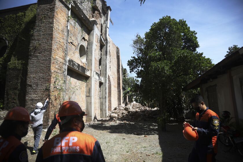 Firemen stand beside a damaged church after a strong earthquake at Ilocos Norte, Northern Philippines on Wednesday Oct. 26, 2022. A strong earthquake rocked a large swathe of the northern Philippines, injuring multiple people and forcing the closure of an international airport and the evacuation of patients in a hospital, officials said Wednesday. (AP Photo)