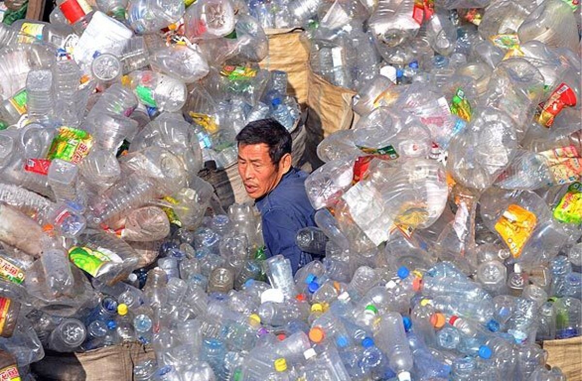 A waste management worker in Shenyang, China, sorts through plastics collected for recycling.