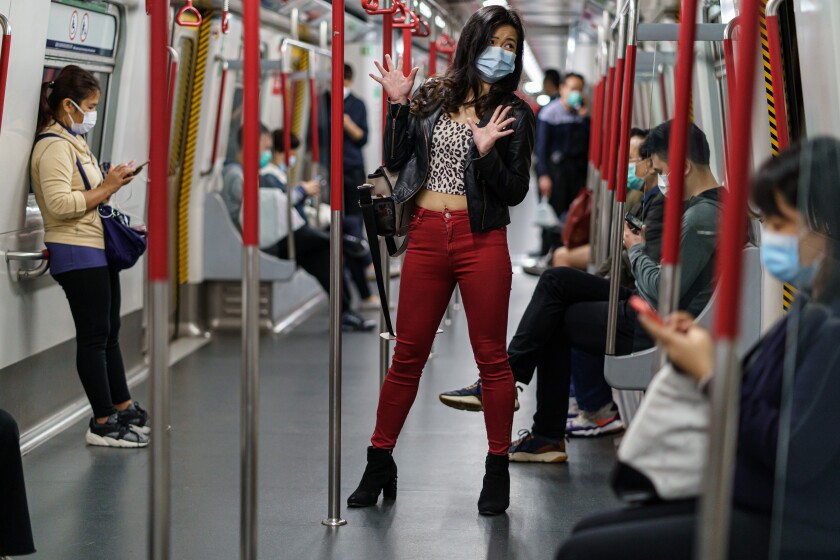 A woman with a facemask standing in a subway car