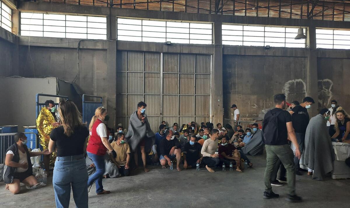 Survivors of a migrant shipwreck sitting in a warehouse