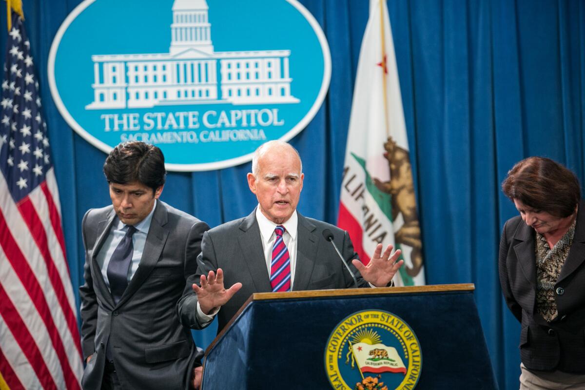 Gov. Jerry Brown Jr., center, talks about gas reduction being dropped from the climate change bill at a Capitol press confrence.