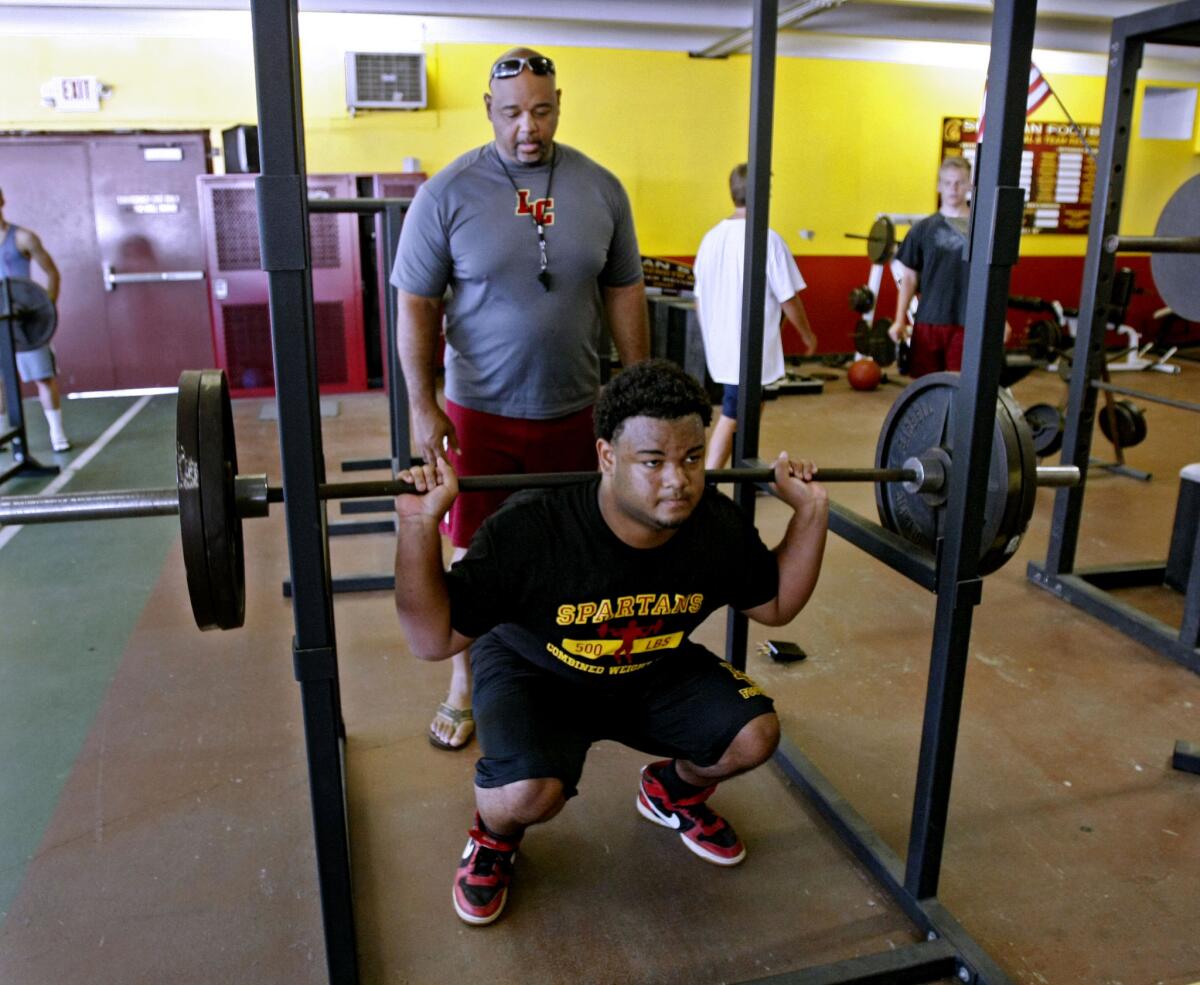 La Canada High School football coach James Sims keeps an eye on his son, senior D'Andre Sims, during workout at the school's gym in La Canada Flintridge on Tuesday, July 9, 2013. The younger Sims, 6'3" and 254 lbs., sat out one year at a school in Florida so he could play defensive end at La Canada High. Schedule-wise, the La Cañada High football team's 2013 season is nearly the exact same as the 2012 one.