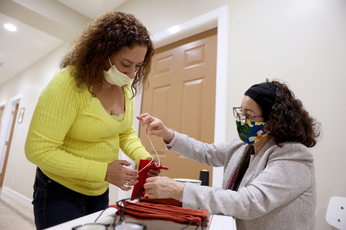 Sisters Vicky Cerpas, left, and Lilia Cerpas, each the owner of businesses closed during the coronavirus crisis, team up to make handmade masks in Santa Ana. 