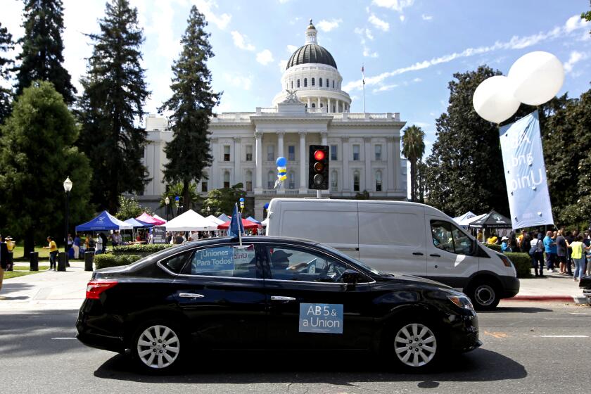 Dozens of supporters of a measure to limit when companies can label workers as independent contractors circle the Capitol during a rally in Sacramento, Calif., Wednesday, Aug. 28, 2019. If approved by the legislature and signed by Gov. Gavin Newsom, AB5, by Assemblywoman Lorena Gonzalez, D-San Diego, would require companies like Uber and Lyft to treat their drivers like employees. (AP Photo/Rich Pedroncelli)