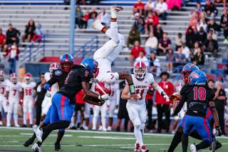 Orange Lutheran quarterback TJ Lateef goes airborne hurdling over Wesley Ace (18) of Gardena Serra. 