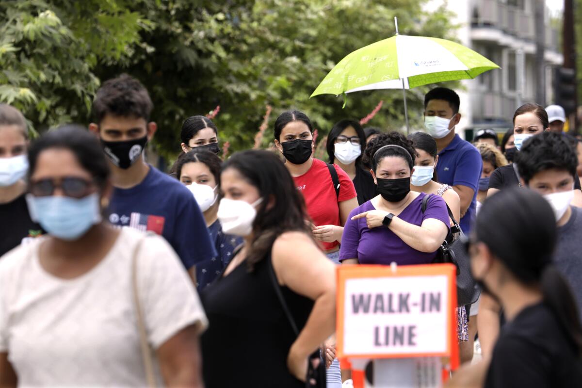 A crowd of families wearing masks wait in line
