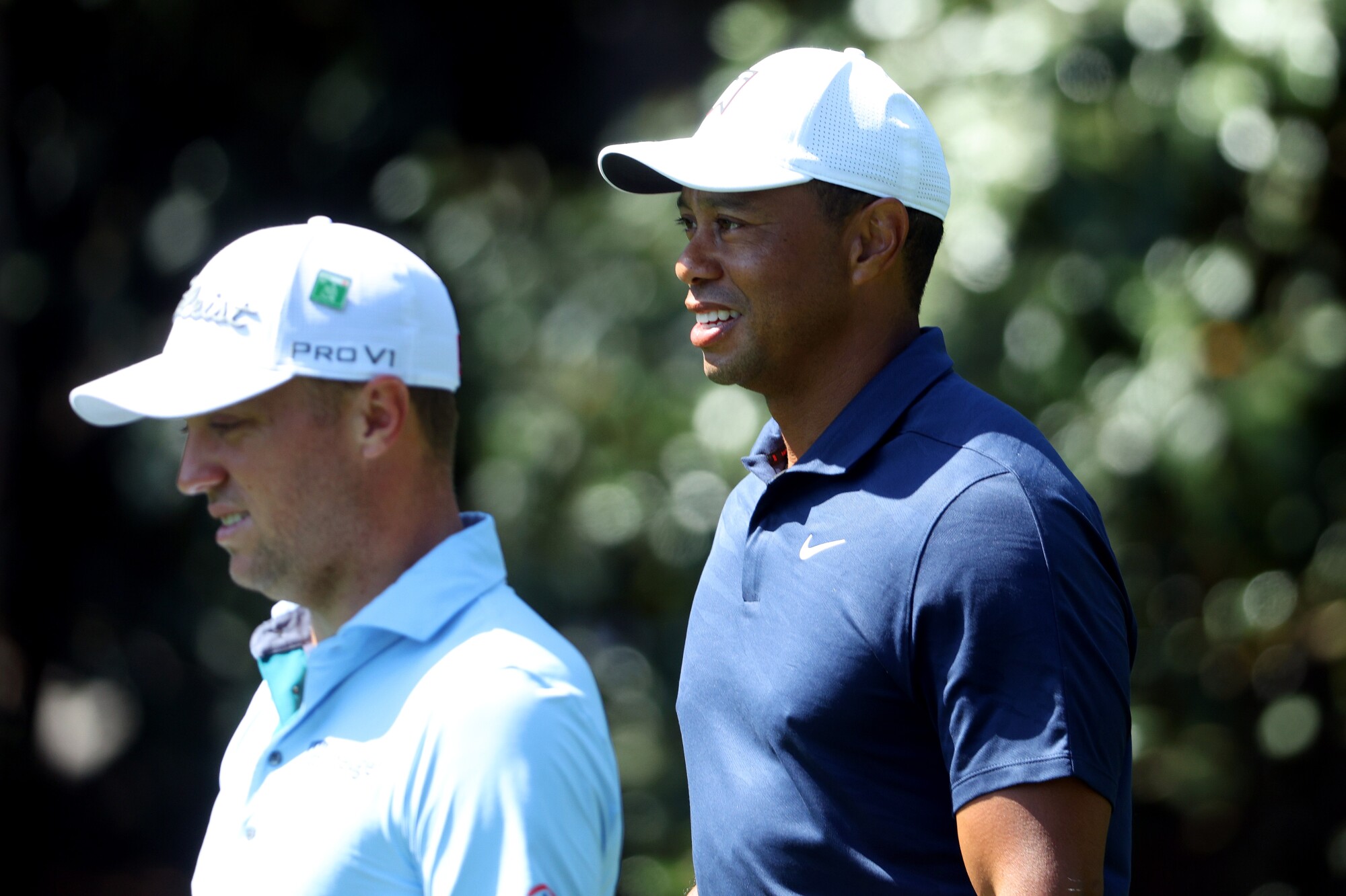 Justin Thomas and Tiger Woods, both wearing caps