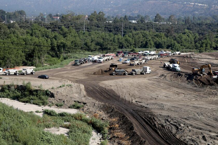 Trucks line up for a quick wash-down before heading out with a load of dirt from the Hahamongna Watershed Park L.A. County Public Works Department's Devil's Gate Dam Sediment Removal project, in La Canada Flintridge on Tuesday, July 30, 2019.
