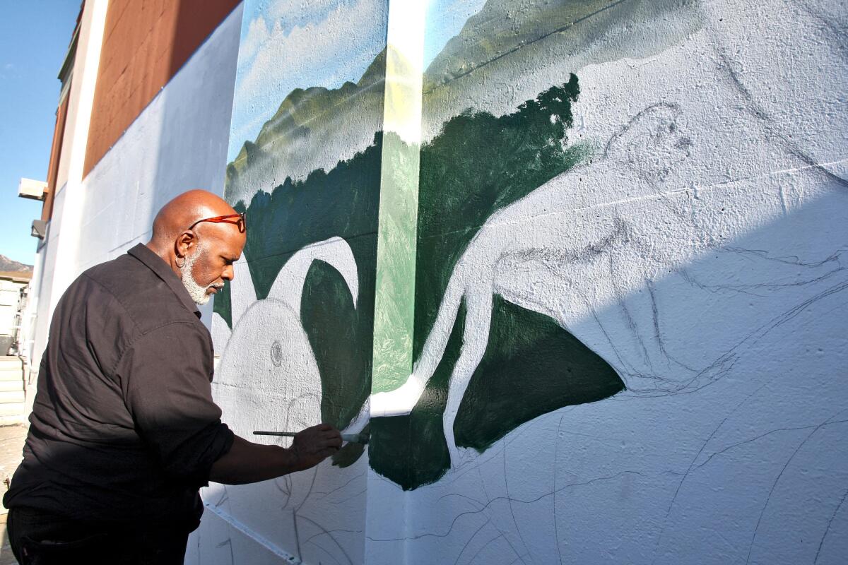 Artist Henry Goods paints a new mural at McKinley Elementary School in Burbank on Tuesday, Nov. 10, 2015. The mural will be 76 feet long and 14 feet tall and will take about five weeks to complete.