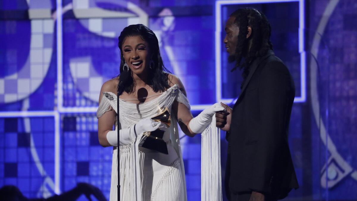 Cardi B accepts an award for best rap album with her husband by her side.