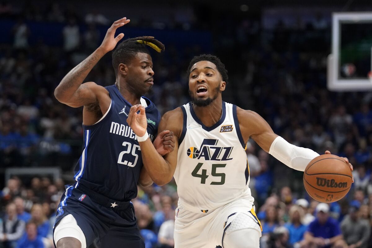 Dallas Mavericks forward Reggie Bullock (25) defends as Utah Jazz guard Donovan Mitchell (45) works to the basket in the first half of Game 1 of an NBA basketball first-round playoff series, Saturday, April 16, 2022, in Dallas. (AP Photo/Tony Gutierrez)