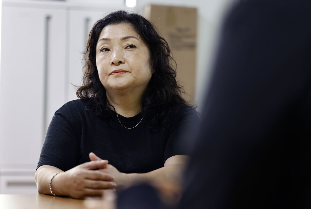 한 여자가 팔을 쭉 뻗고 테이블 위에 손을 모으고 앉아 있다