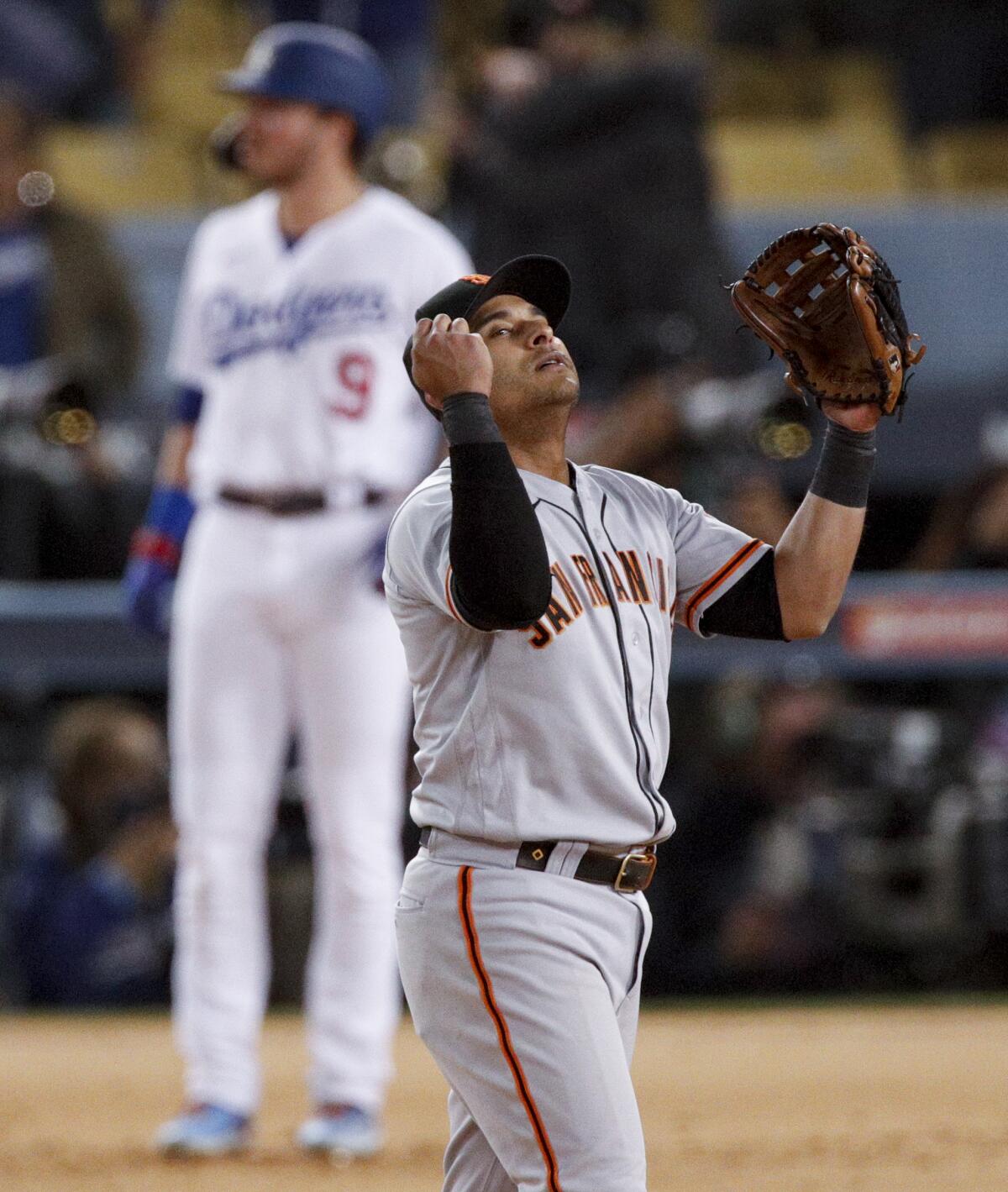 Giants second baseman Donovan Solano celebrates as Dodgers hitter Gavin Lux stands stunned.