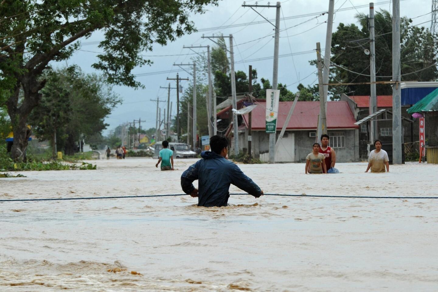A resident holds onto a rope as he negotiates a flood along a submerged highway in Santa Rosa, Philippines, on Oct. 19, 2015, a day after typhoon Koppu hit Aurora province.