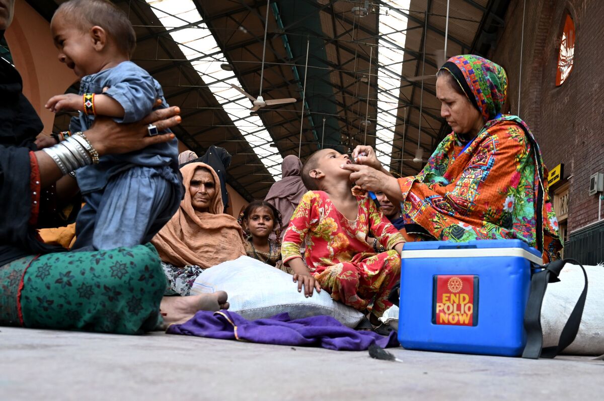 A Pakistani health worker administers polio drops to a child