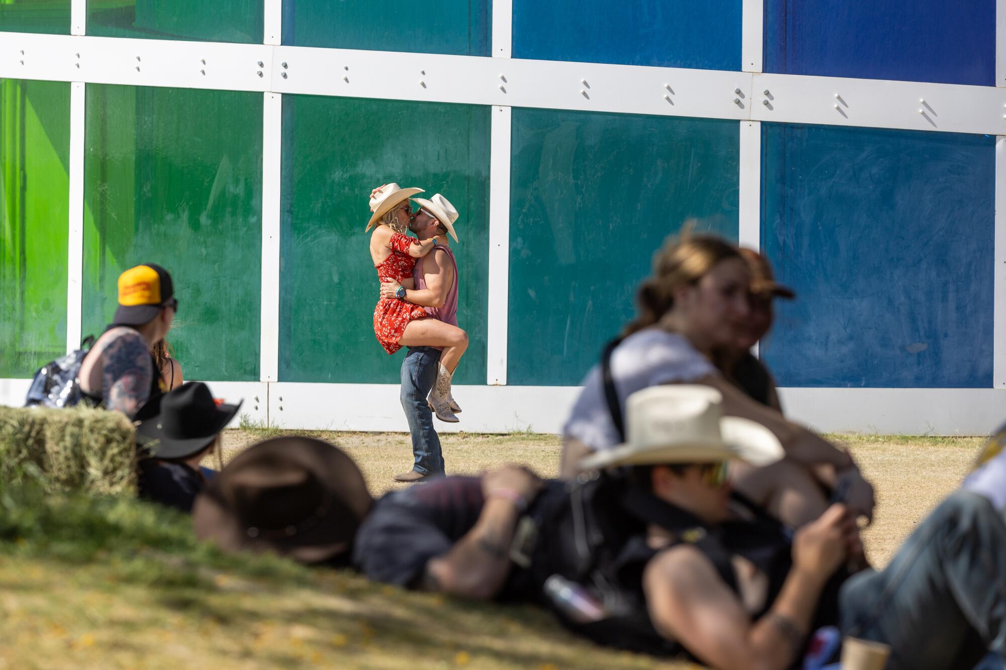A couple kisses as other nap and rest in the shade at the Stagecoach Country Music Festival.