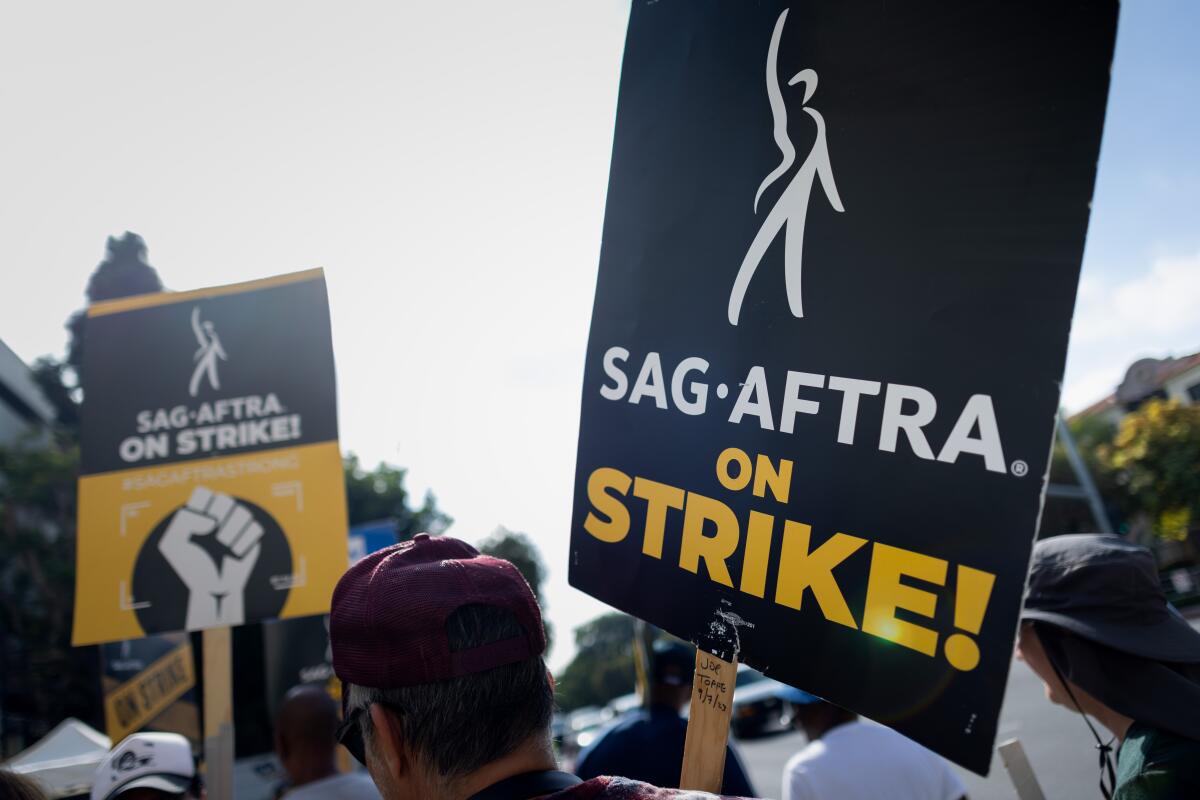 People carrying picket signs that read, "SAG-AFTRA on Strike!"