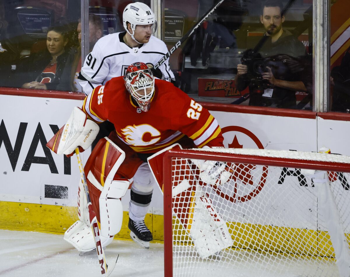 Los Angeles Kings forward Carl Grundstrom, rear, is checked by Calgary Flames goalie Jacob Markstrom during the third period of an NHL hockey game Tuesday, March 28, 2023, in Calgary, Alberta. (Jeff McIntosh/The Canadian Press via AP)