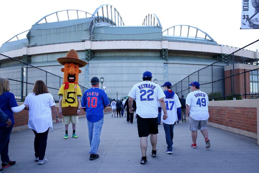 Cubs fans arriving for a game against the Brewers at Miller Park pass by the chorizo, one of the famous racing sausages that entertain fans at Brewers games.