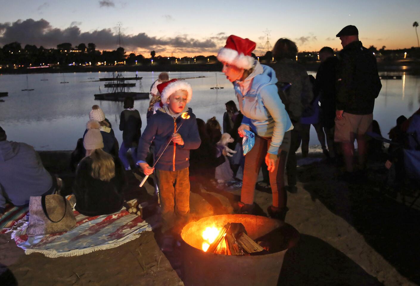 Patrick Horan, and his mom Lenka blow out the flames on a marshmallow around the fire as they wait for the annual Dunes Waterfront Resort tree lighting ceremony and Santa arrival on Friday.