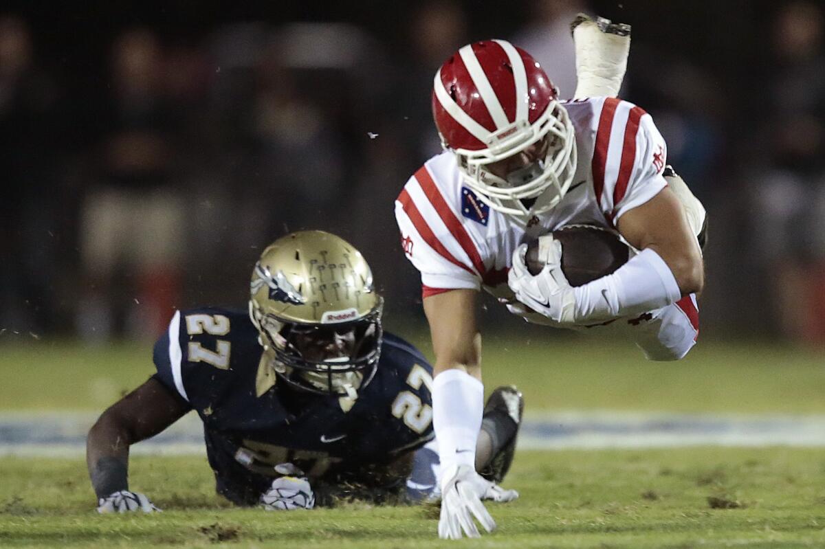 Mater Dei running back Noah Delgadillo, right, is tripped by St. John Bosco defensive back D.J. Morgan during the second quarter of Friday's game.