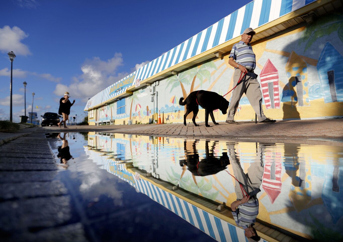 Beachgoers walk past a mural along the boardwalk as Hurricane Florence approaches the east coast in Atlantic Beach, N.C., Wednesday, Sept. 12, 2018.