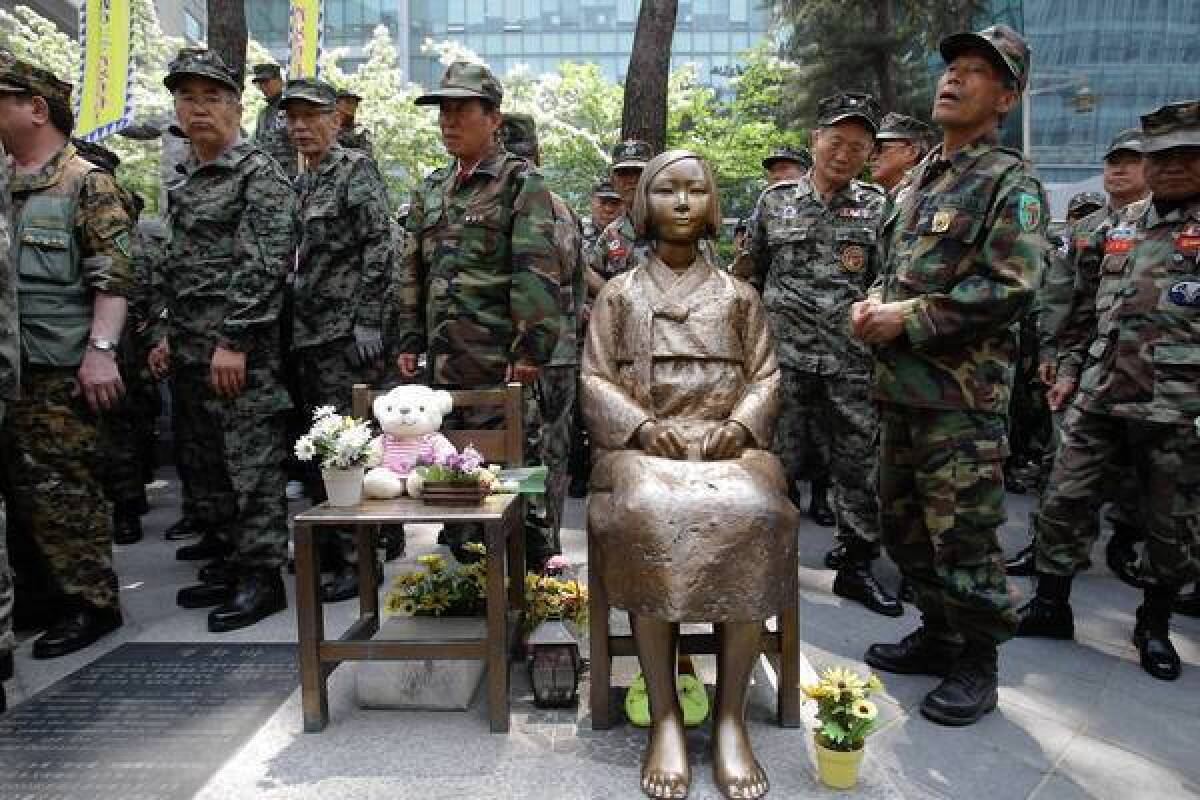 South Korean Vietnam War veterans stand beside a statue honoring "comfort women" during a rally in front of the Japanese Embassy in Seoul. Remarks by the mayor of Osaka on the historic perception of "comfort women," coerced into Japanese military brothels during World War II, have drawn intense criticism from neighboring countries and the United States.