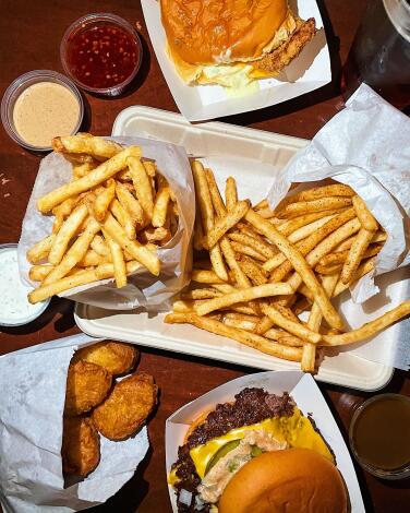 An overhead of fries (at center), a cheeseburger, chicken nuggets, sauces and fish sandwich from Love Hour in Koreatown.