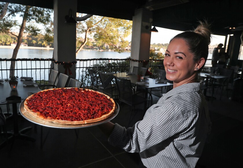 Server Suzanne Miller holds the most popular dish at Domenico's, the ground pepperoni pizza in the new lakeside patio.