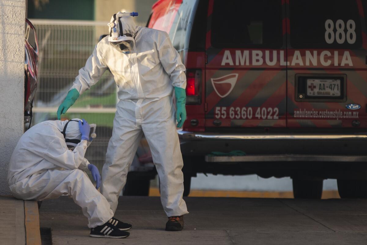 A paramedic in a protective suit comforts a colleague, also in a protective suit, at the Hospital de las Américas in Ecatepec, Mexico City, on May 2, 2020.