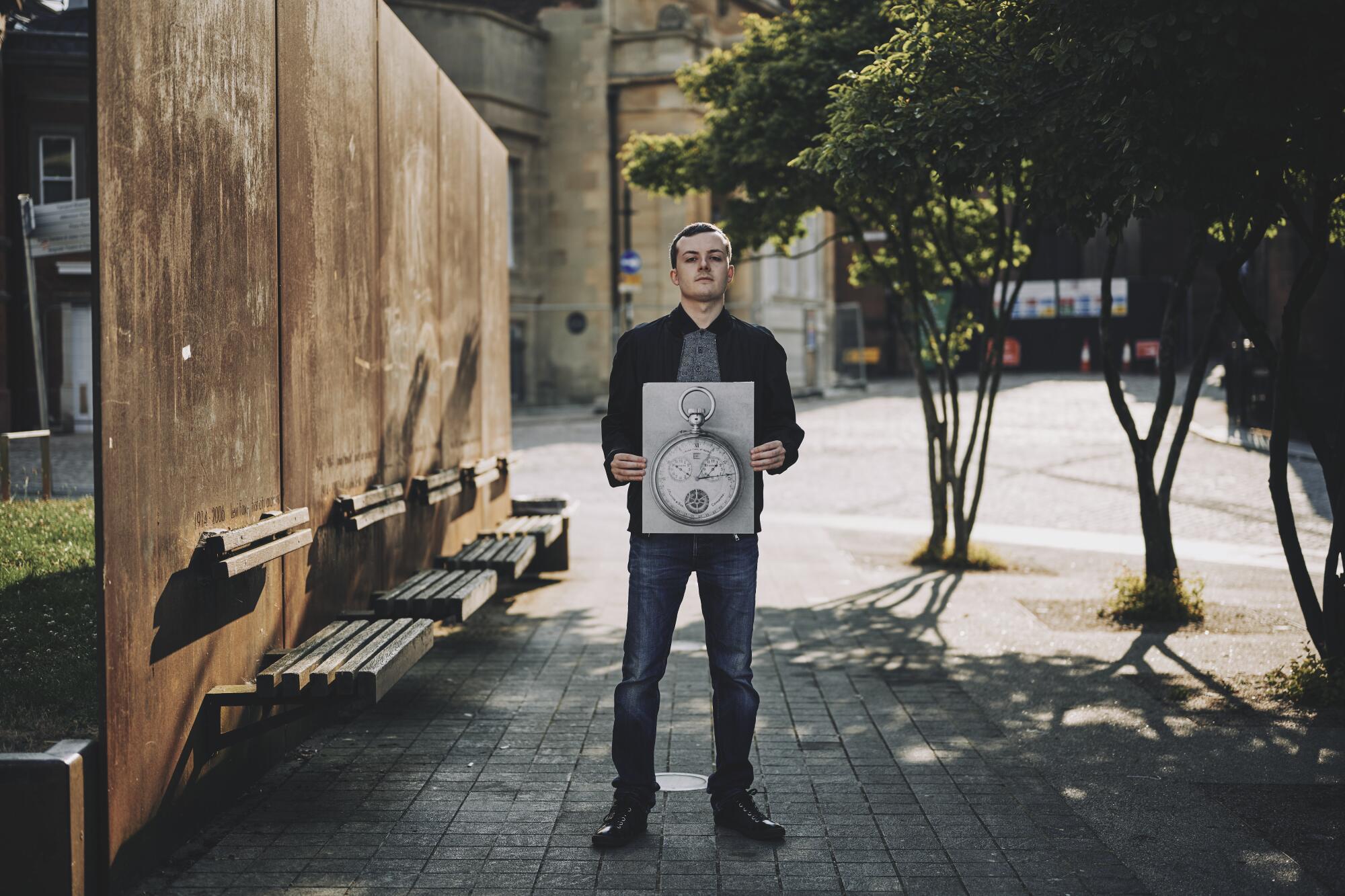 Carl Player holding a large photo of the J. Player & Son timepiece