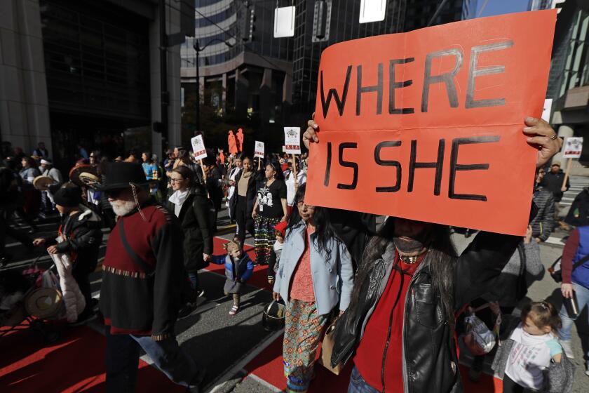 FILE - Dennis Willard, of Bellevue, Wash., carries a sign that reads "Where Is She" as he marches in support of missing and murdered indigenous women during a rally to mark Indigenous Peoples' Day in downtown Seattle, on Oct. 14, 2019. Washington Gov. Jay Inslee has signed into law a bill that creates a first-in-the-nation statewide alert system for missing Indigenous people. The law creates a system similar to Amber Alerts and so-called silver alerts, which are used respectively for missing children and vulnerable adults in many states. (AP Photo/Ted S. Warren, File)