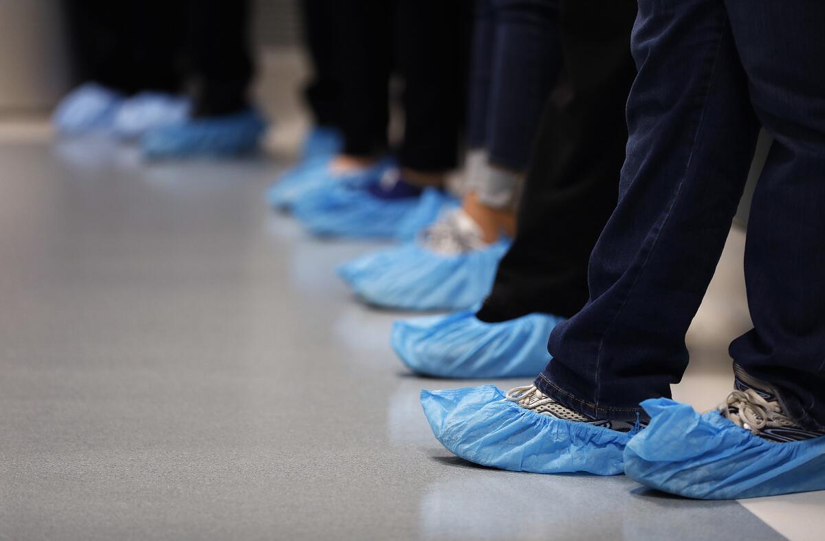 Visitors wear shoe covers during an open house at  OneLegacy's Transplant Recovery Center in Redlands in March 2018. 