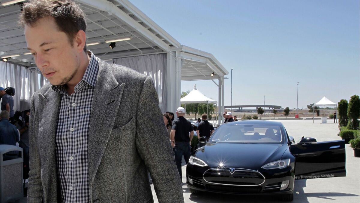Elon Musk is seen in 2012 leaving a news conference where he blamed a shortage of lithium-ion battery cells for trouble meeting demand for the Model S. (Paul Sakuma / AP)