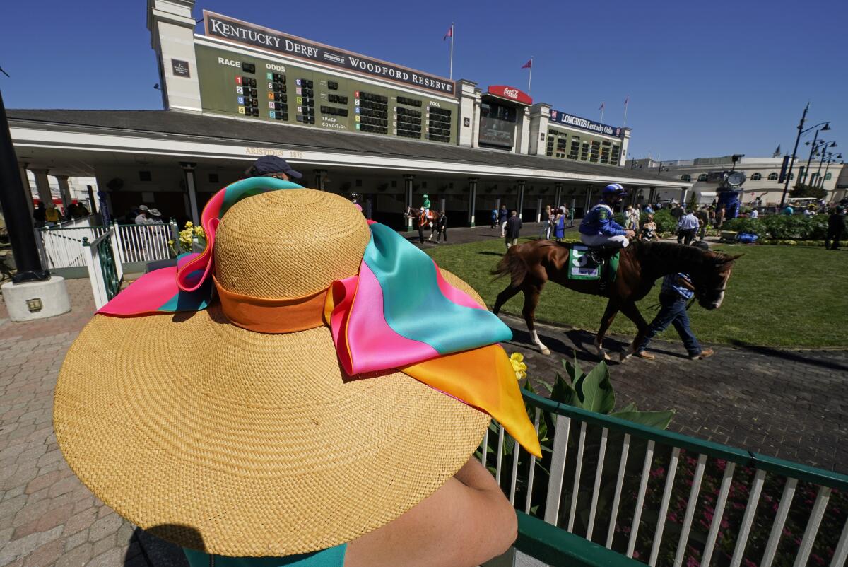 A guest watches as horses walk through the paddock before the 146th running of the Kentucky Derby.