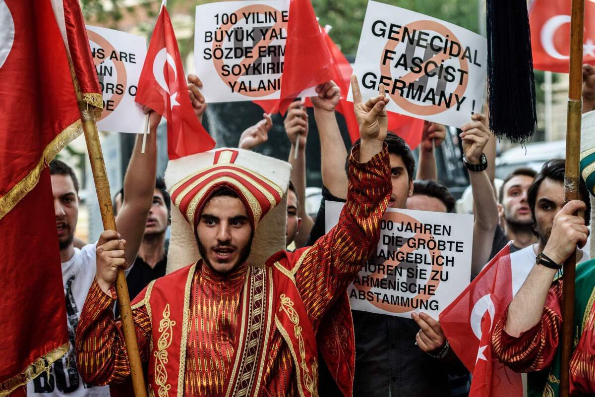 Turkish nationalist protesters flash the nationalist organization's "grey wolf" sign and hold placards during a protest against Germany on June 2, 2016 in front of the Germany consulate in Istanbul after German parliament labeled the World War I massacre of Armenians by Ottoman forces as genocide.