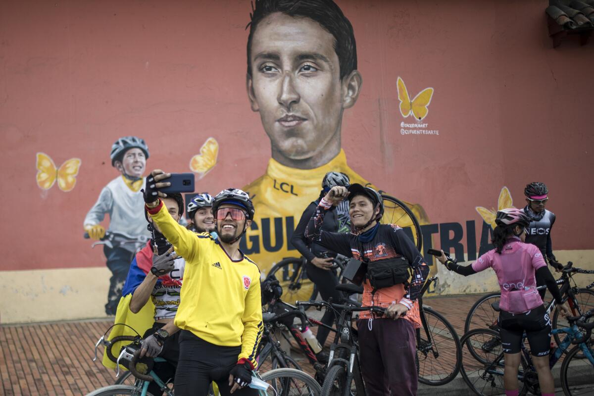 Unos ciclistas se reúnen frente a un mural del ciclista colombiano Egan Bernal