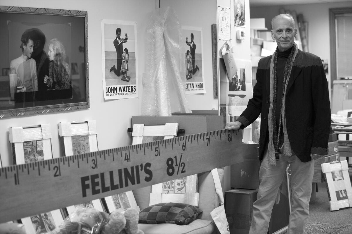 John Watters stands next to his artwork.