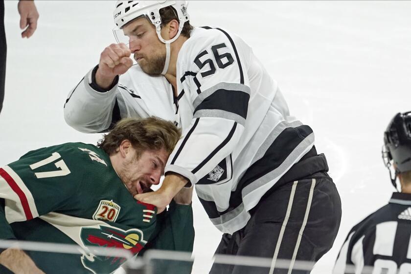 Minnesota Wild's Marcus Foligno (17) ducks away from a punch thrown by Los Angeles Kings' Kurtis MacDermid (56) in the first period of an NHL hockey game, Thursday, Jan. 28, 2021, in St. Paul, Minn. Both received fighting majors. (AP Photo/Jim Mone)