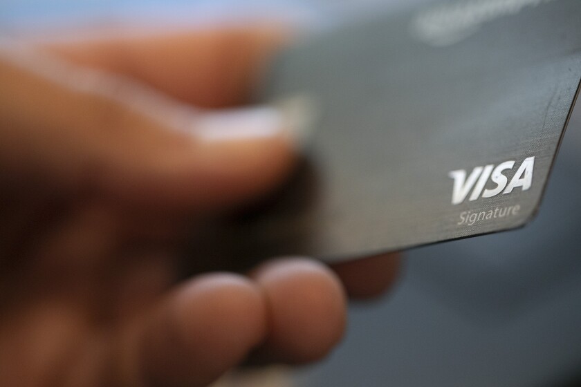 FILE - This Aug. 11, 2019, file photo shows a Visa logo on a credit card in New Orleans. Credit union credit cards are sometimes overlooked when ads for bank-issued credit cards and their many perks steal focus. But you may be missing out if you don’t consider these cards as potential candidates for your wallet. Sometimes credit union credit cards have rich offers or provide value in the form of lower fees and interest rates. (AP Photo/Jenny Kane, File)