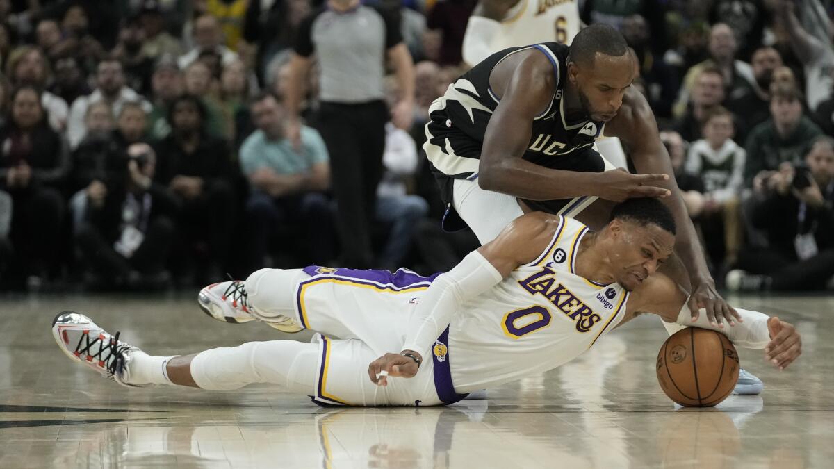 Lakers guard Russell Westbrook dives to the court to beat Bucks forward Khris Middleton to a loose ball.